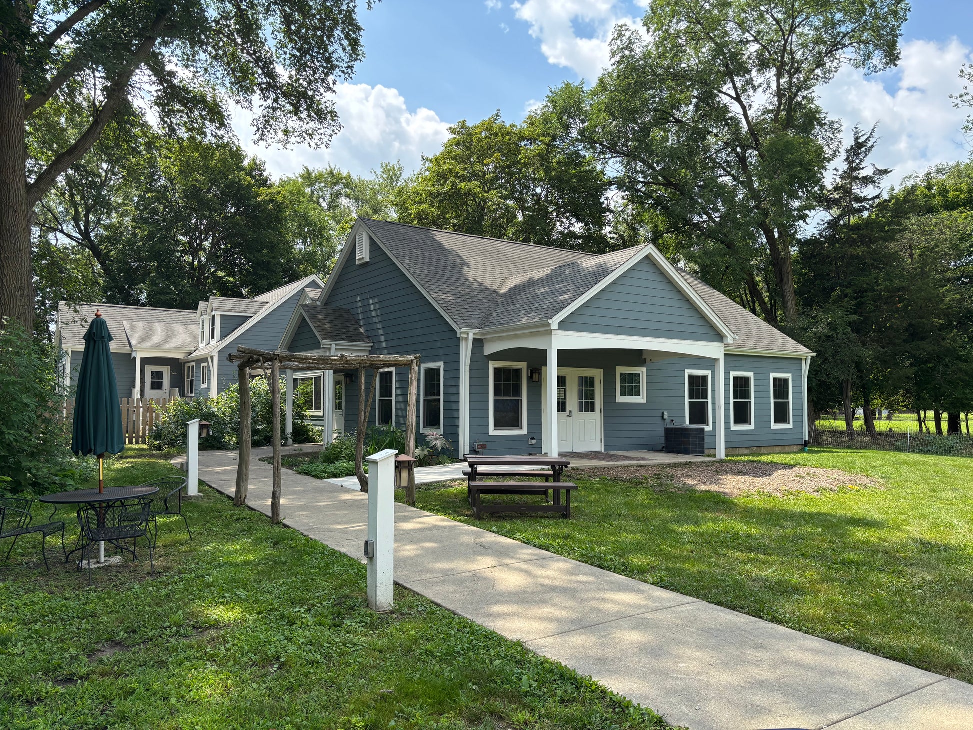 Blue house with a covered porch and outdoor furniture on a sunny day.