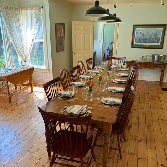Dining room with wooden table and chairs, plates, and glasses set for a meal.