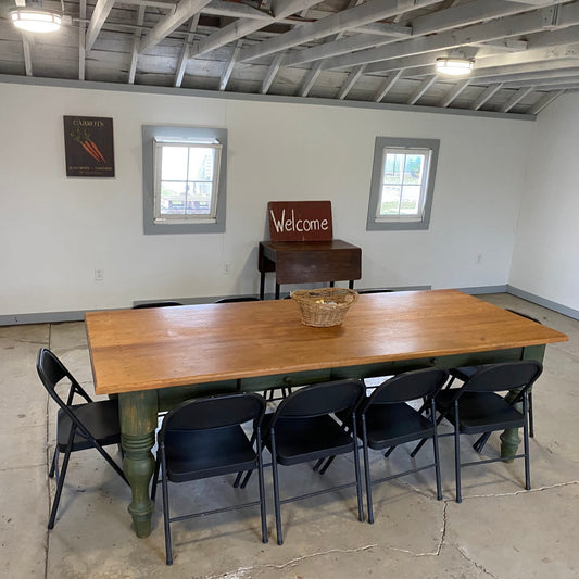 Wooden table with chairs in a room with white walls and concrete floor.